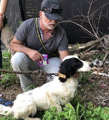 Jon Barocas kneeling beside a rescued dog outdoors.