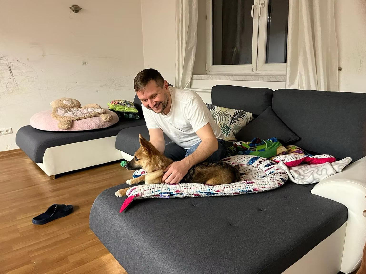 Rafał Sikora smiling with a rescued dog indoors.